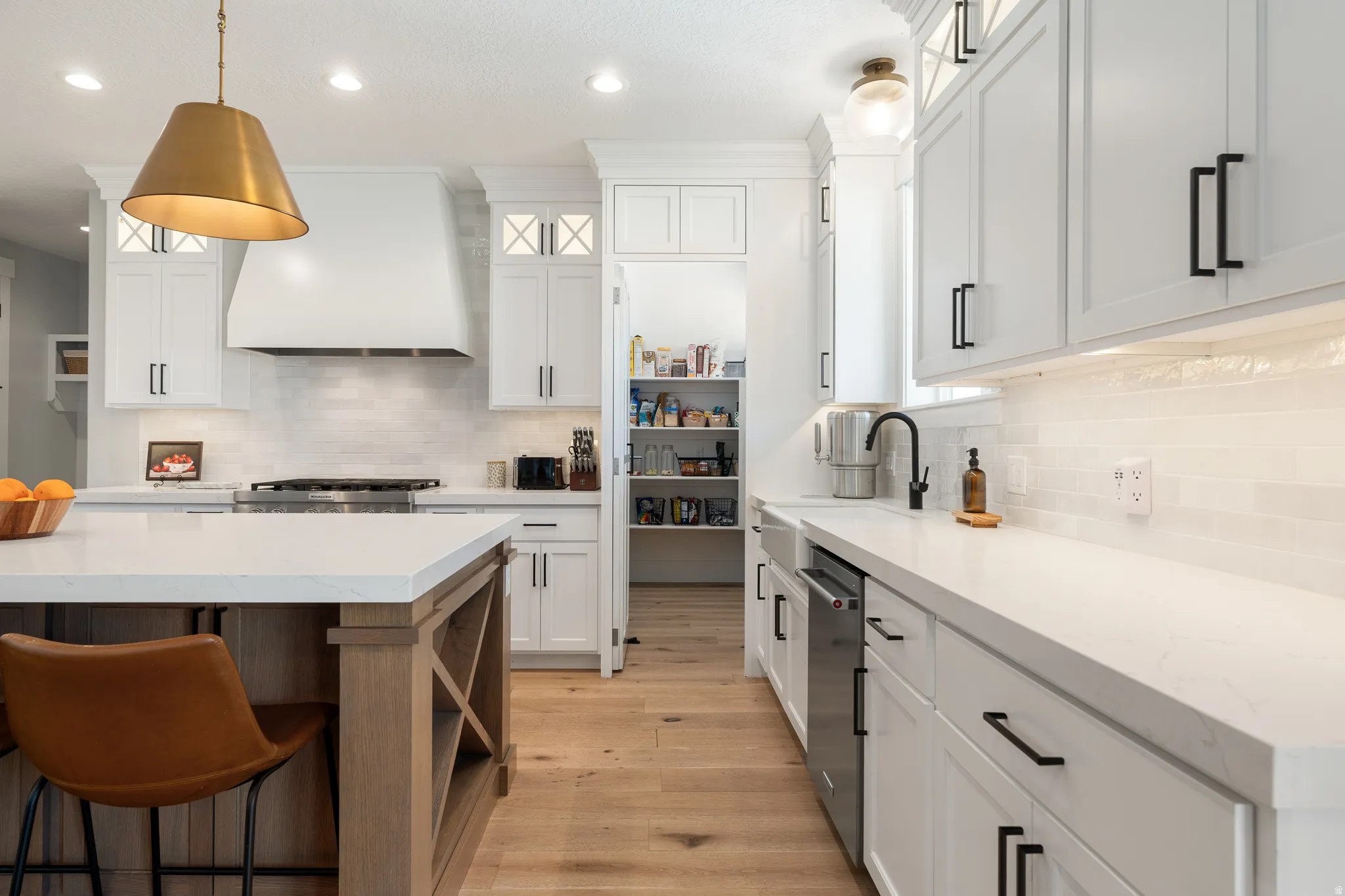 Dual tone kitchen featuring a kitchen bar, light wood-style floors, open shelves, light stone counters, and two tone cabinets