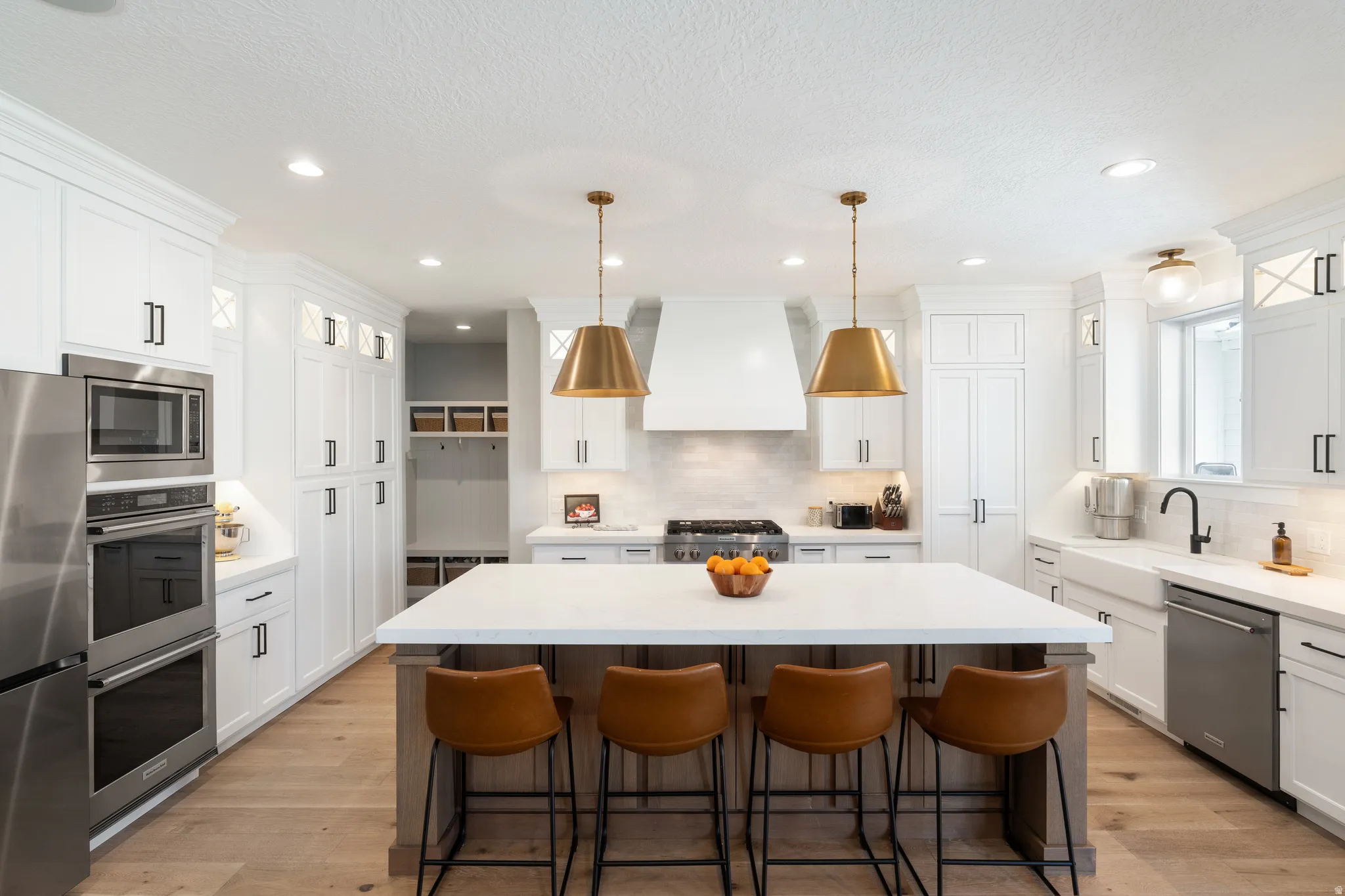 Two tone kitchen featuring a center island, stainless steel appliances, a kitchen breakfast bar, decorative light fixtures, and light wood finished floors