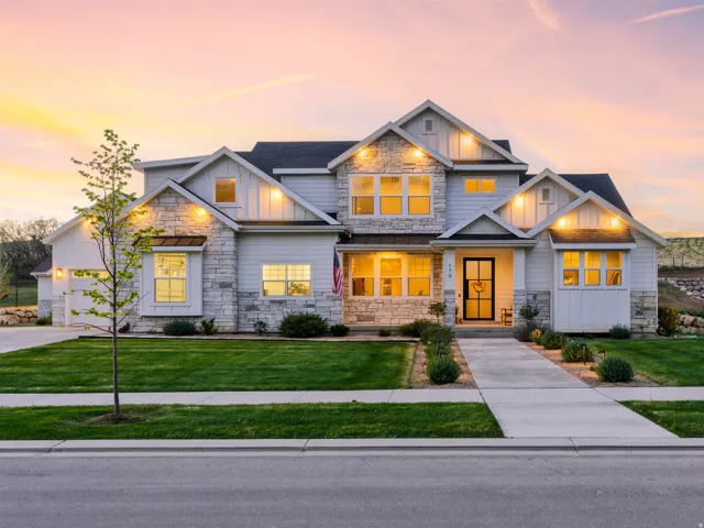 Craftsman inspired home with stone siding, board and batten siding, a yard, driveway, and a garage