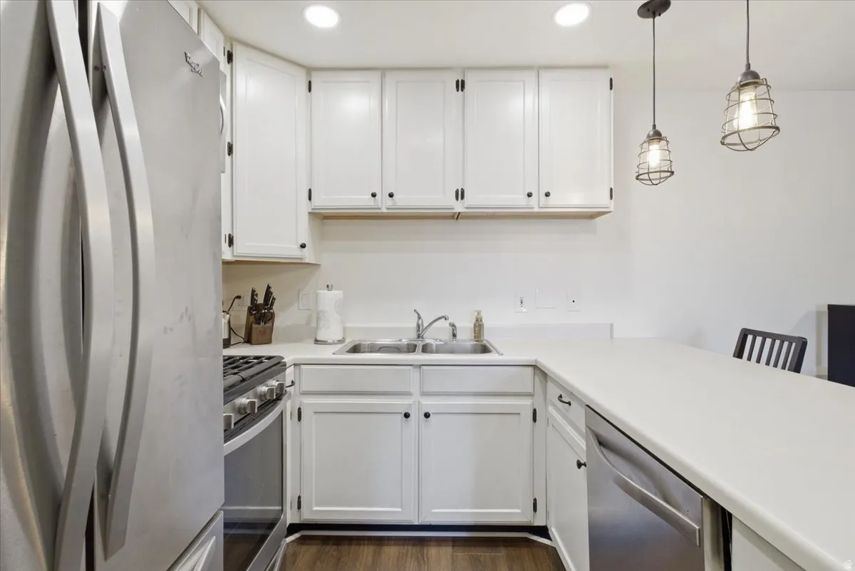 Kitchen featuring stainless steel appliances, white cabinets, light countertops, and pendant lighting