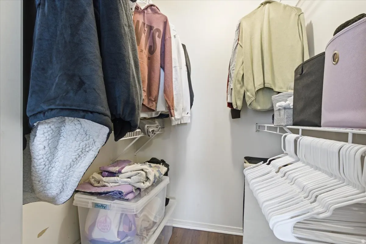 Walk in closet with dark wood-type flooring