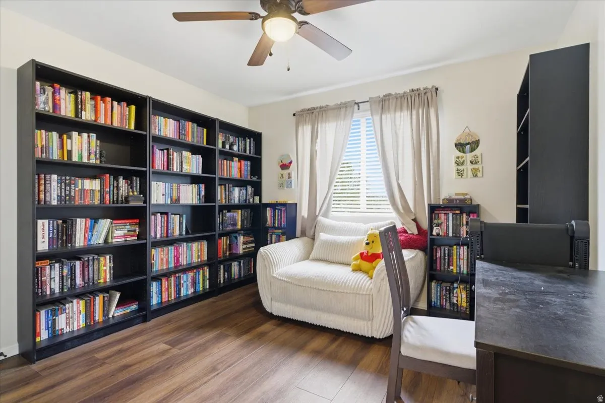 Living area featuring ceiling fan and dark wood-type flooring