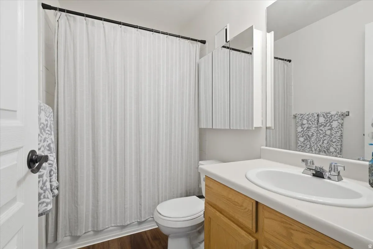Bathroom with vanity, dark wood-type flooring, and shower / bathtub combination with curtain