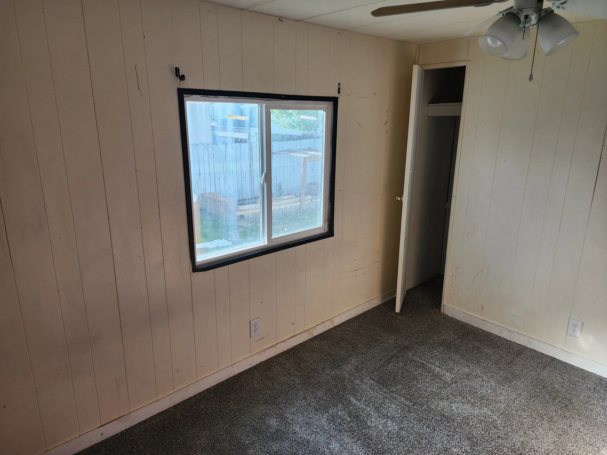 Unfurnished bedroom featuring wooden walls and dark carpet