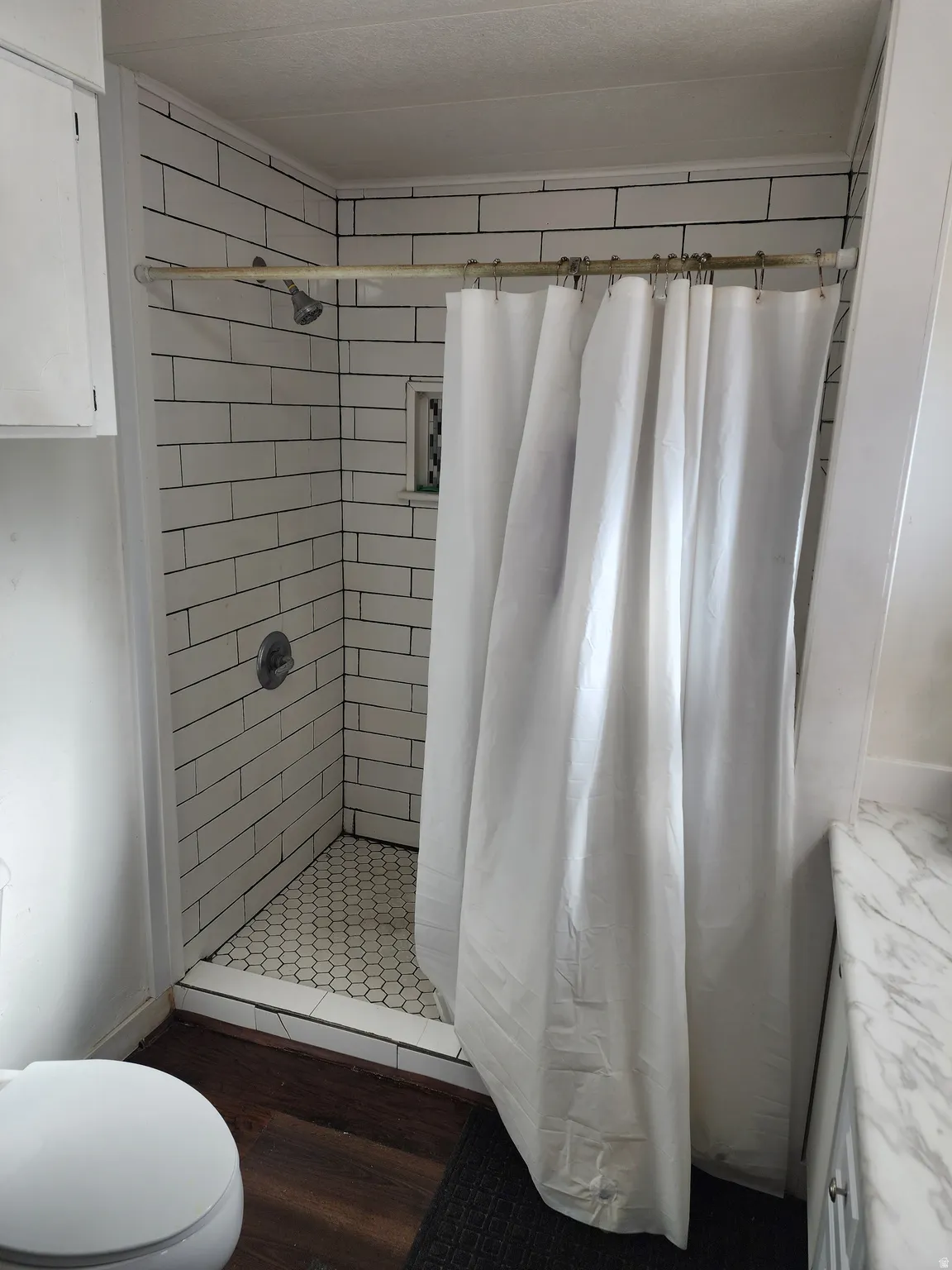 Full bath with a shower stall, dark wood-style floors, and vanity