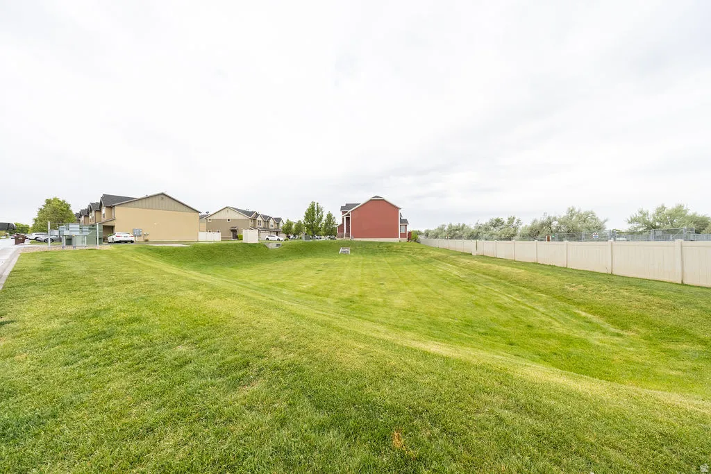 Expansive green space featuring a sloped lawn and a perimeter fence
