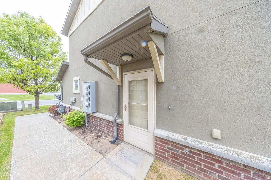 Entryway featuring a covered porch, stucco exterior, and brick lower facade