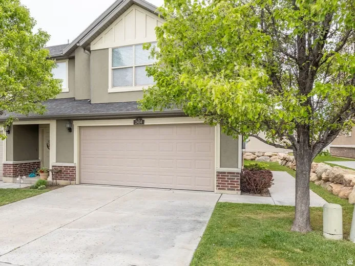 Two-story stucco and brick exterior featuring a multi-panel garage door, front porch entry, and architectural shingles