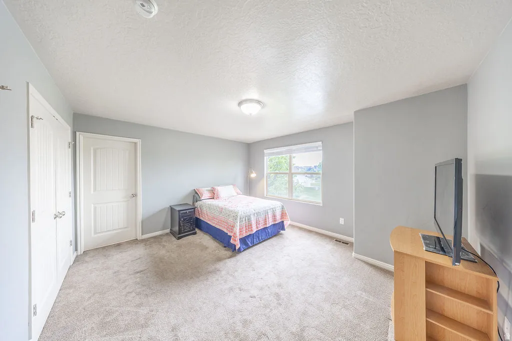 Spacious primary bedroom featuring light gray walls and plush gray carpeting