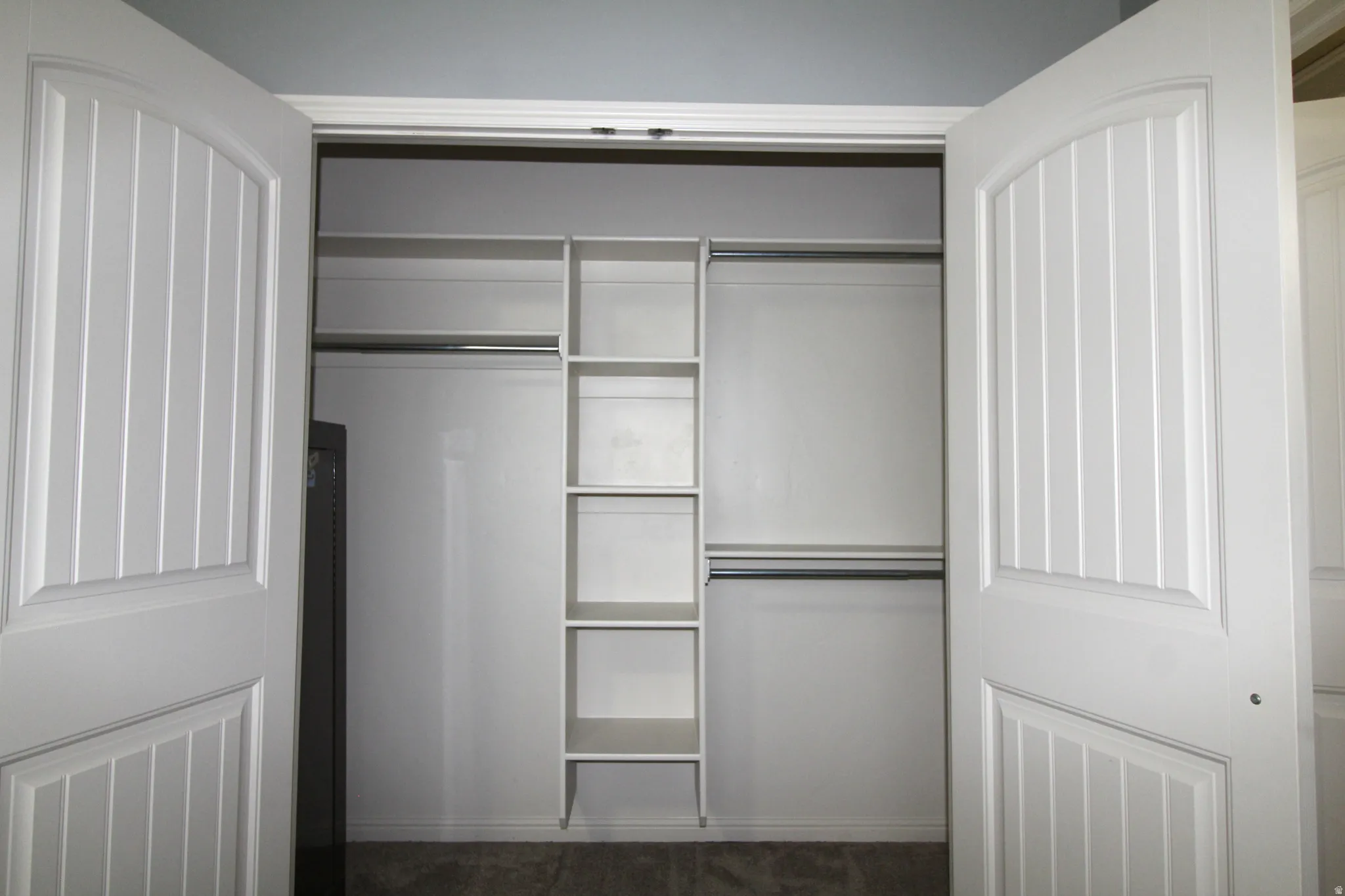 Primary bedroom closet featuring bi-fold doors with vertical paneling, integrated shelving, and dual hanging rods