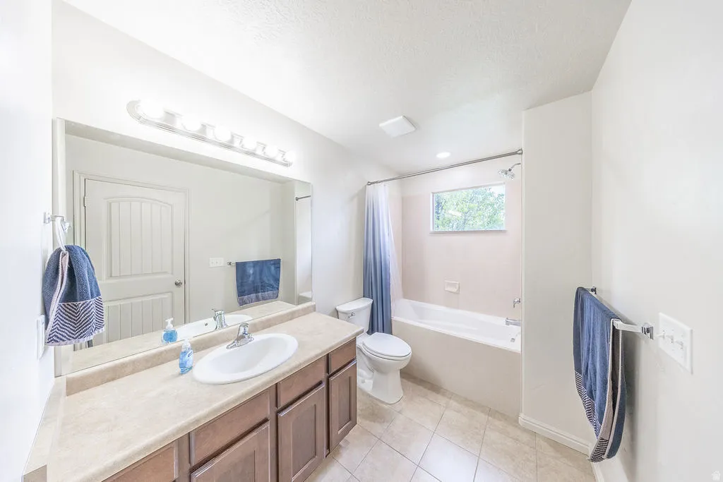 Primary bathroom featuring a single vanity with wood-finish cabinetry, a large mirror, and overhead strip lighting