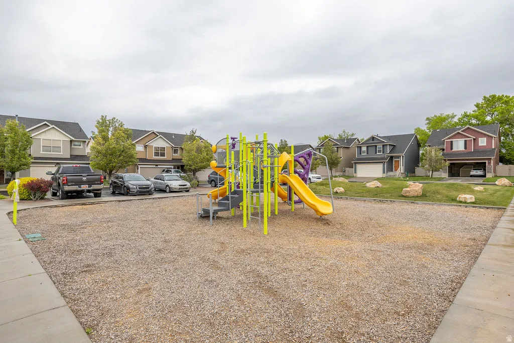 Community playground featuring a yellow slide and purple accents, surrounded by wood chip surfacing