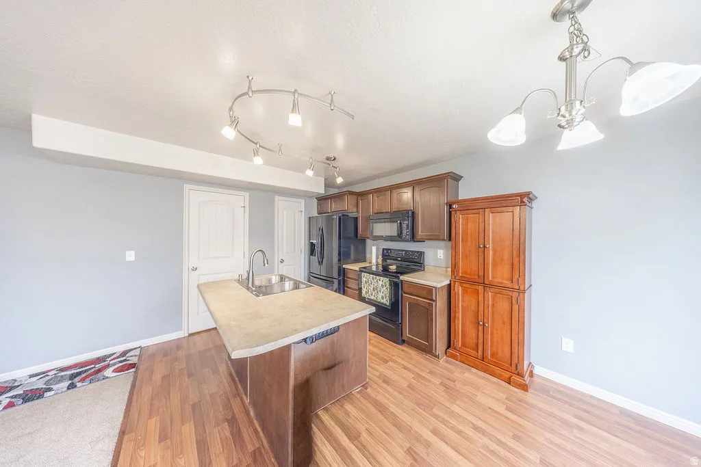 Kitchen featuring wood-finish flooring, dark wood cabinetry, and a central island with an integrated sink