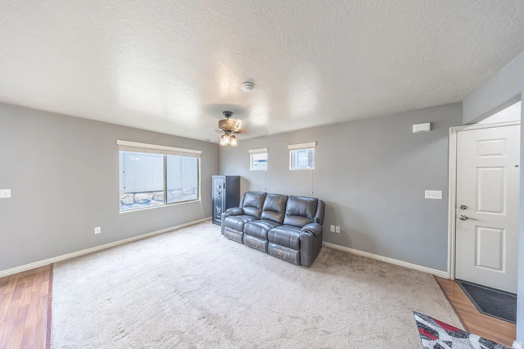 Spacious interior featuring neutral gray walls and a combination of wood-finish flooring and plush carpeting