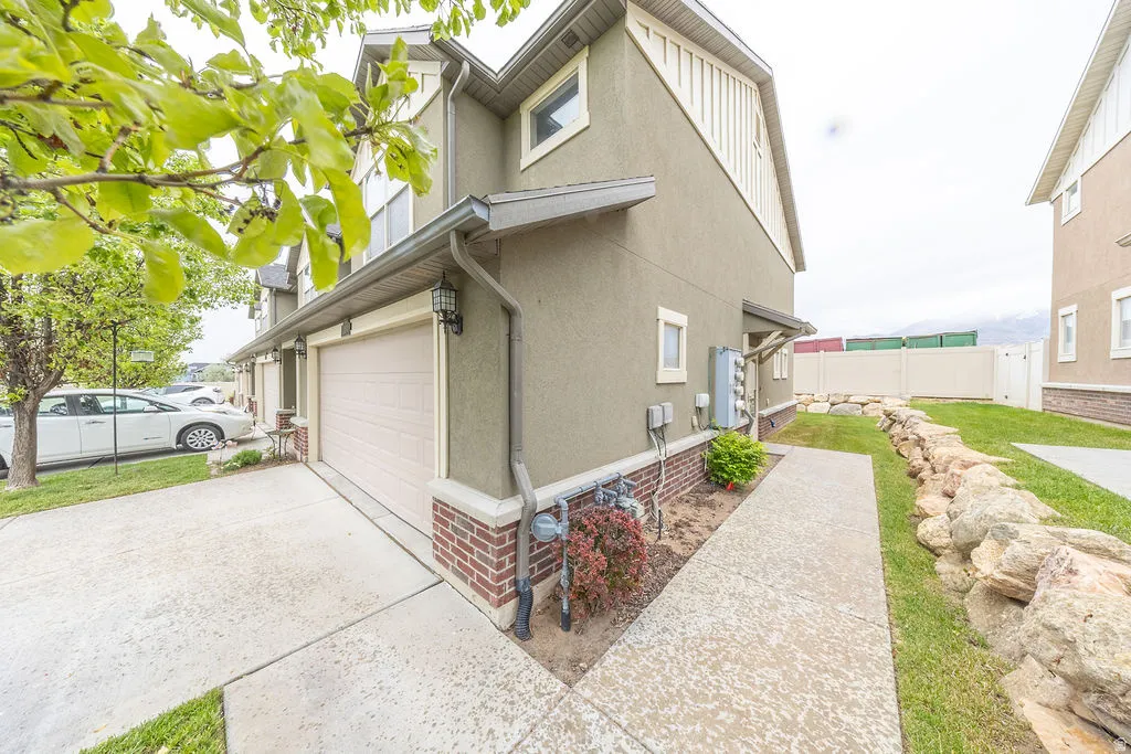 Exterior featuring stucco siding with brick veneer accents, an attached garage, and a concrete driveway