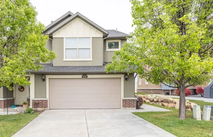 Two-story stucco exterior featuring a prominent two-car garage, brick accents, and a gabled roofline