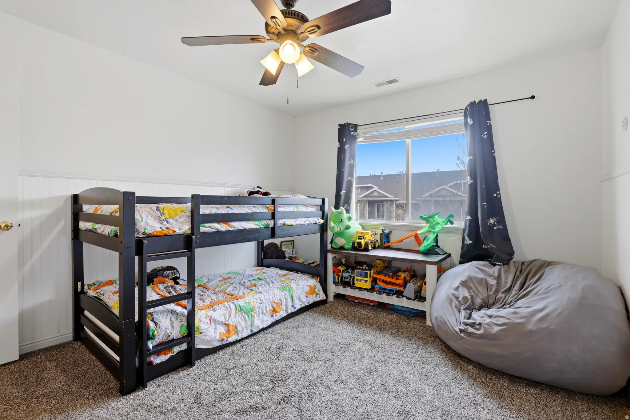 Bedroom featuring carpet, a ceiling fan, and wainscoting