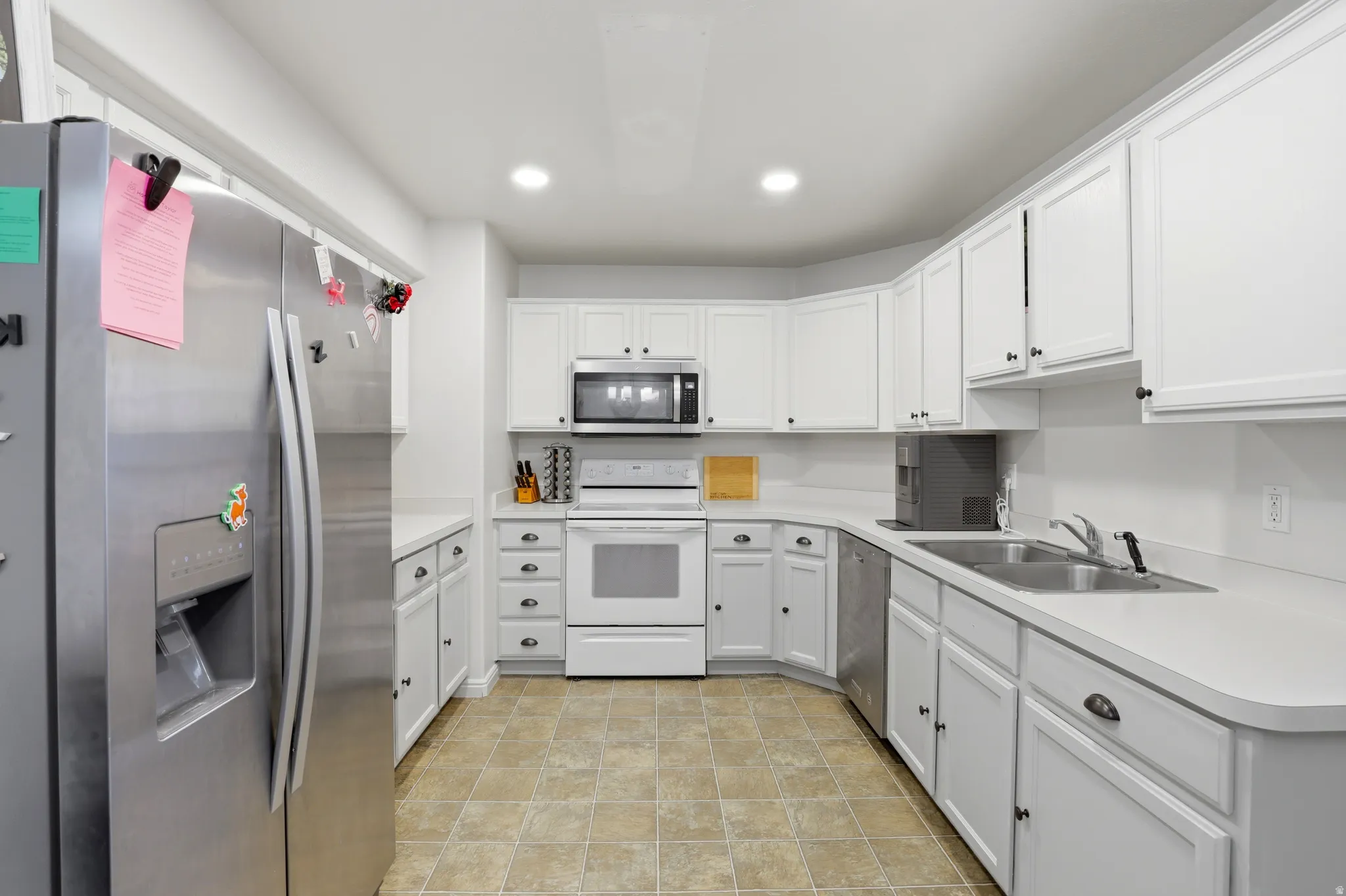 Kitchen featuring stainless steel appliances, light countertops, white cabinets, and recessed lighting