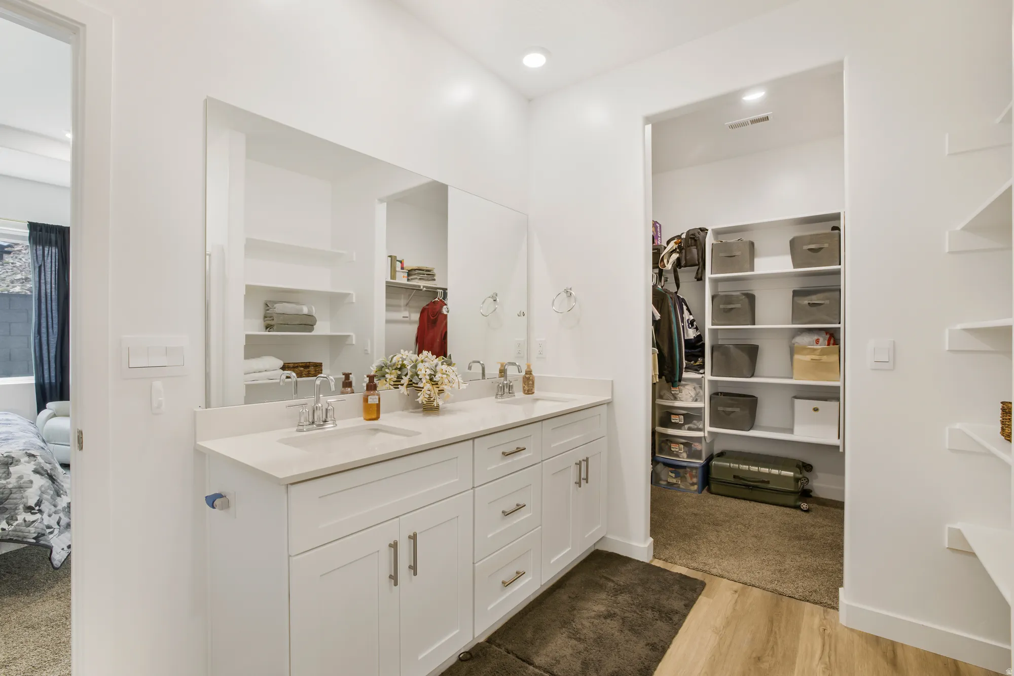 Ensuite bathroom featuring double vanity, light wood-type flooring, a spacious closet, and recessed lighting