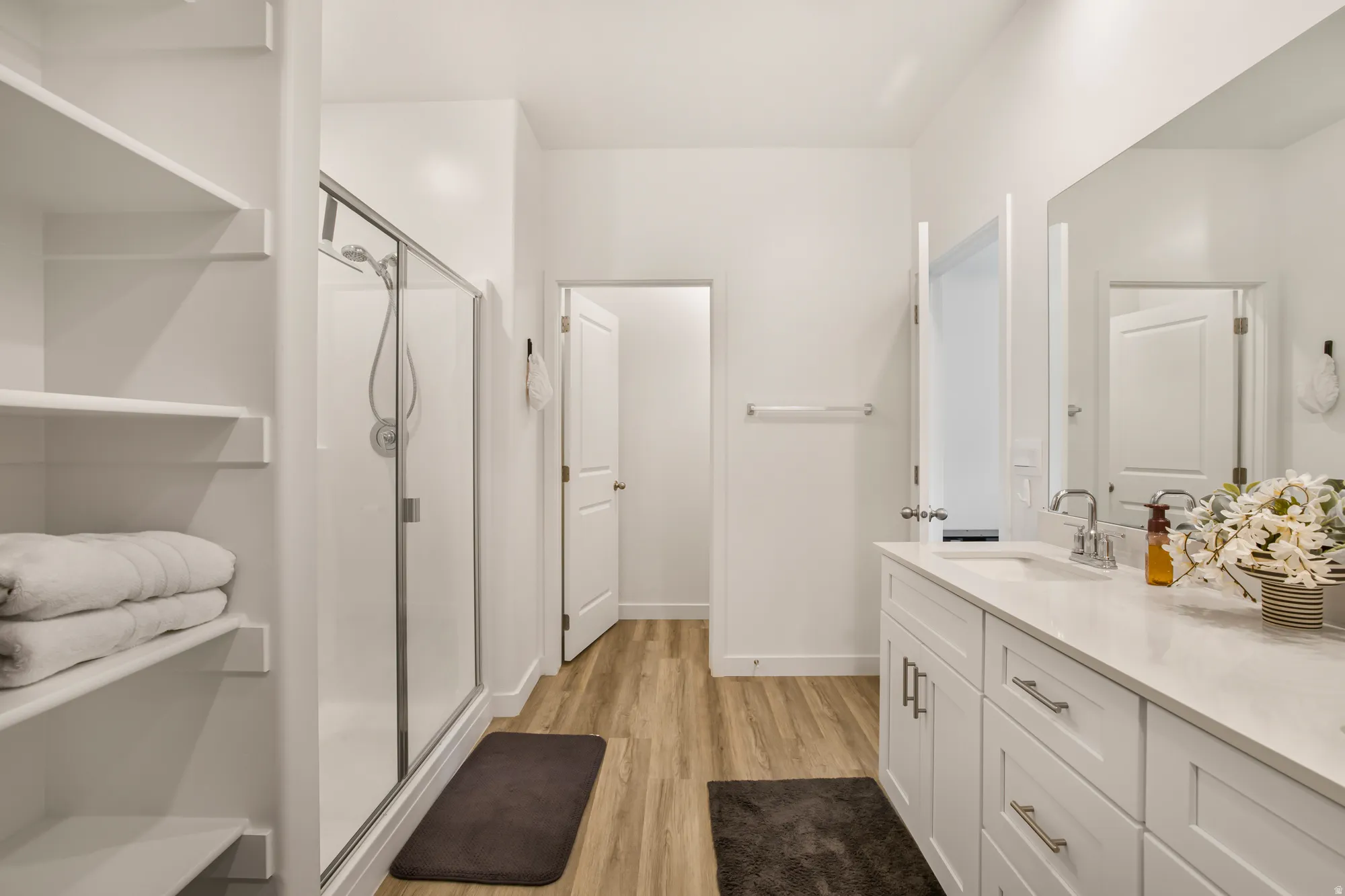 Full bath with a stall shower, vanity, and light wood-type flooring