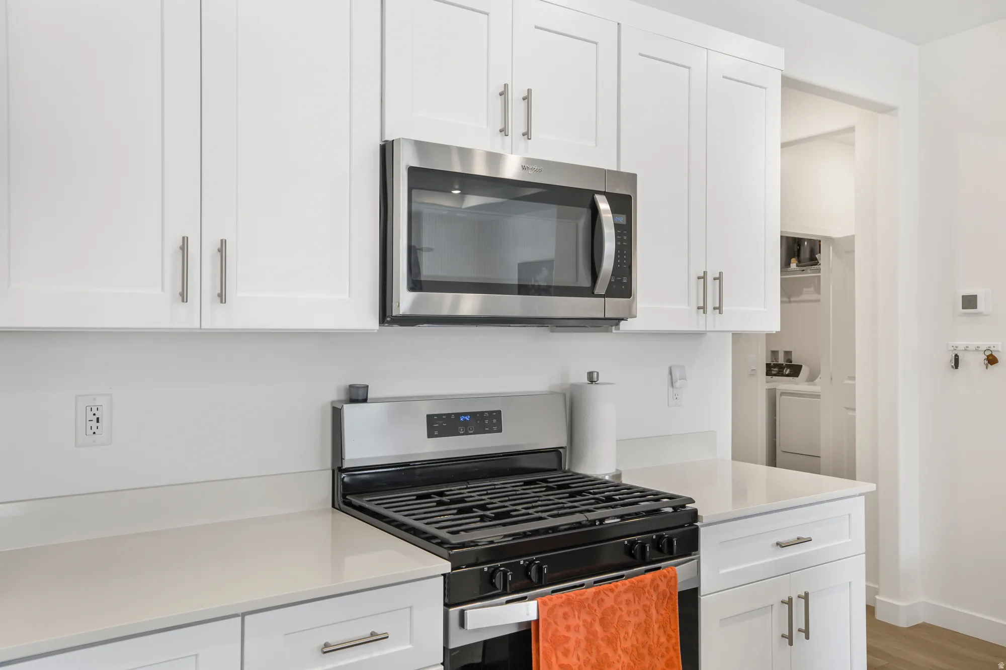 Kitchen with stainless steel appliances, white cabinetry, and light wood-type flooring