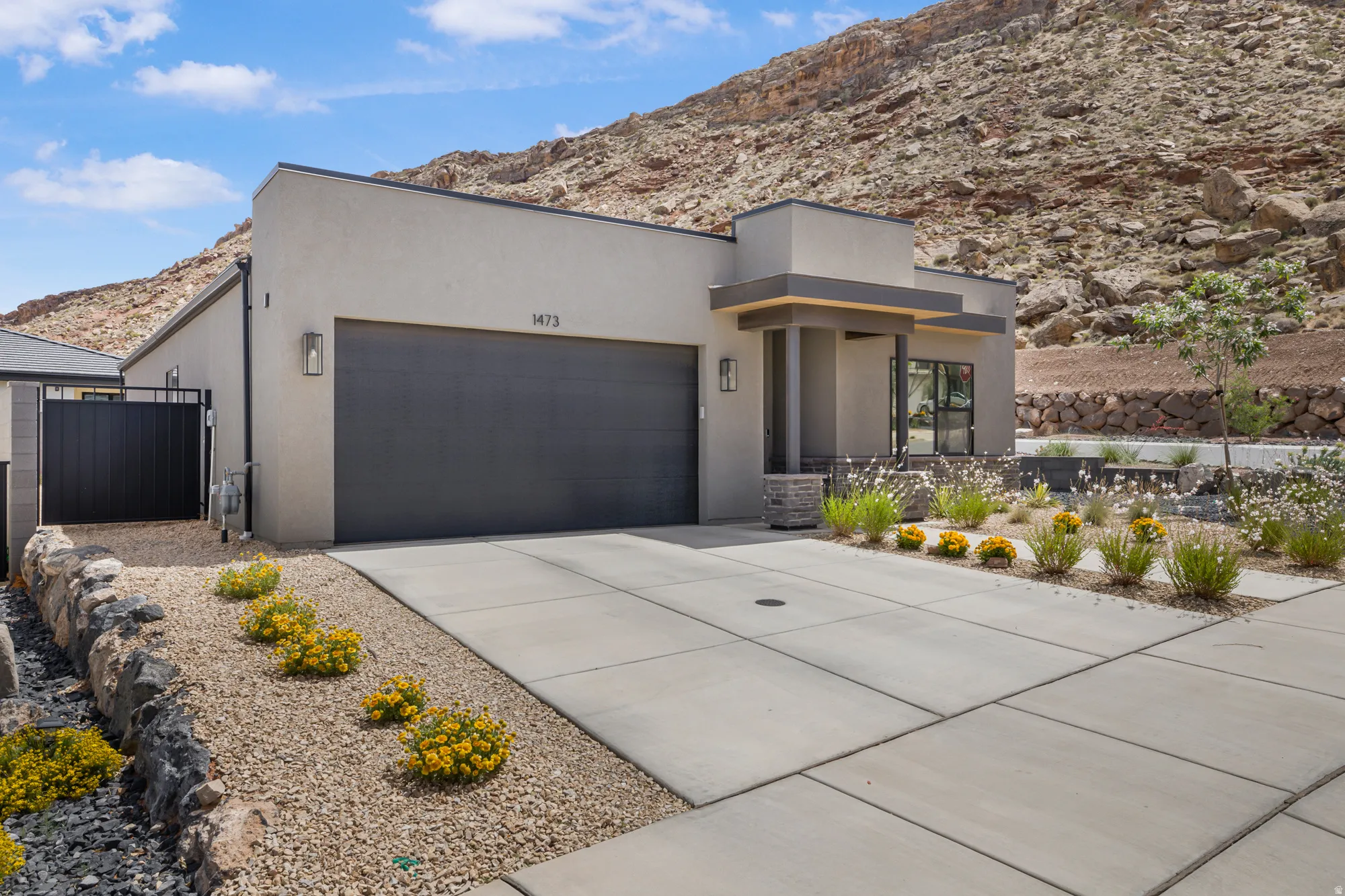 Contemporary house with a mountain view, driveway, a garage, stucco siding, and a gate