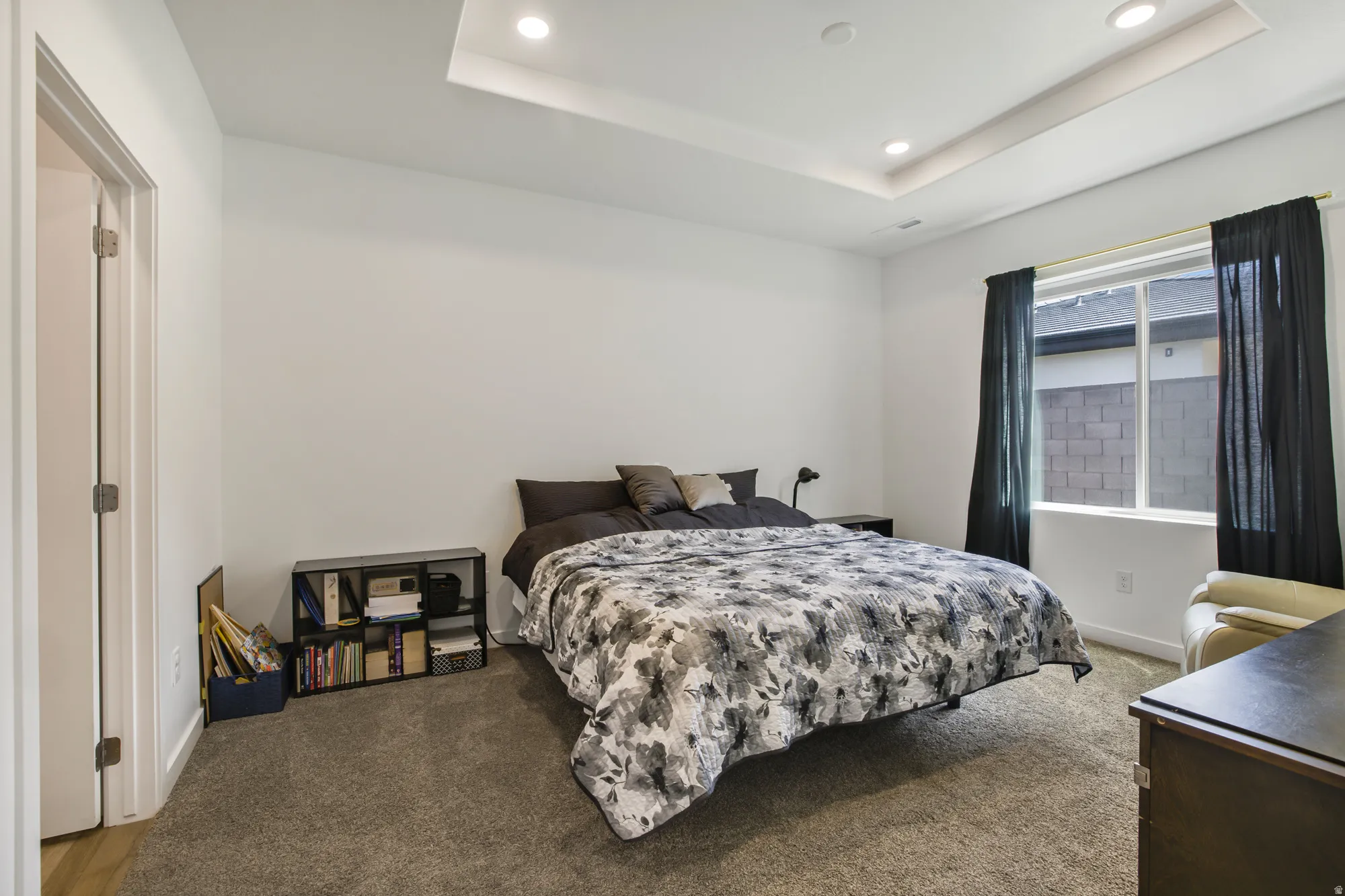 Carpeted bedroom featuring recessed lighting and a tray ceiling