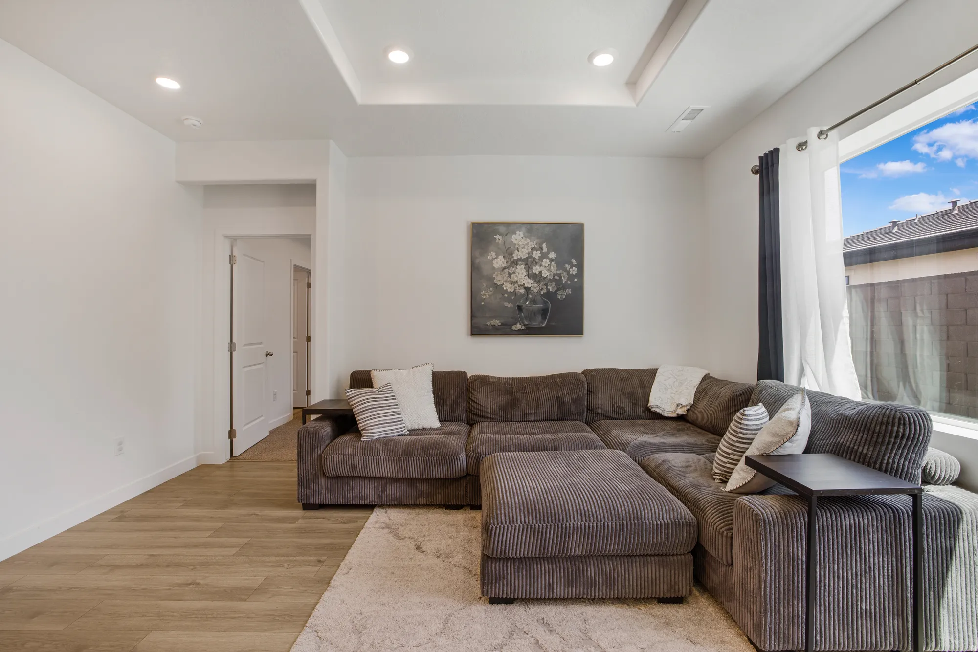 Living area featuring recessed lighting, light wood-type flooring, and a tray ceiling
