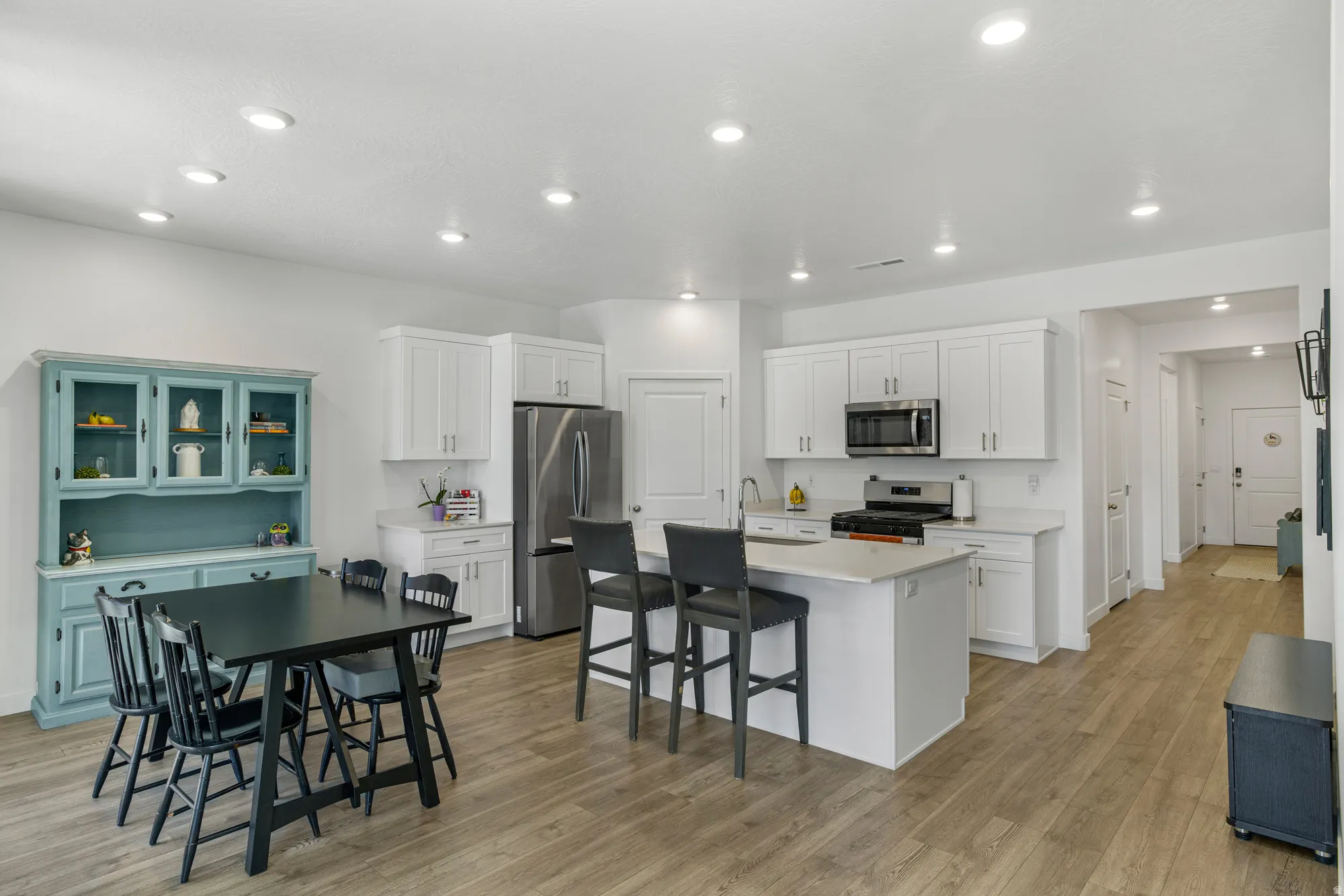 Kitchen with white cabinets, stainless steel appliances, a breakfast bar, a kitchen island with sink, and recessed lighting