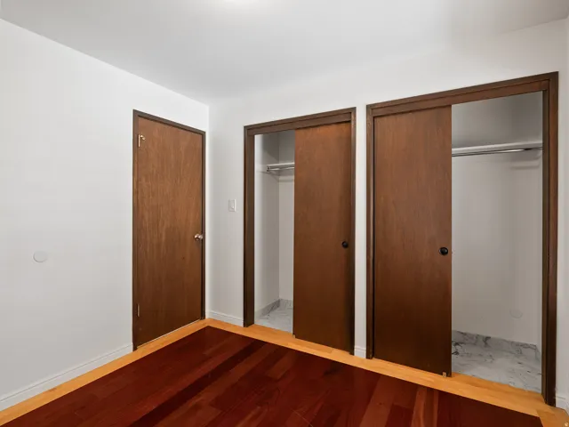 Unfurnished bedroom with multiple closets and light wood-style flooring