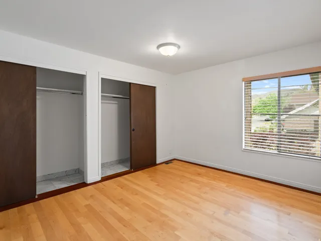 Unfurnished bedroom featuring multiple closets and light wood-style flooring