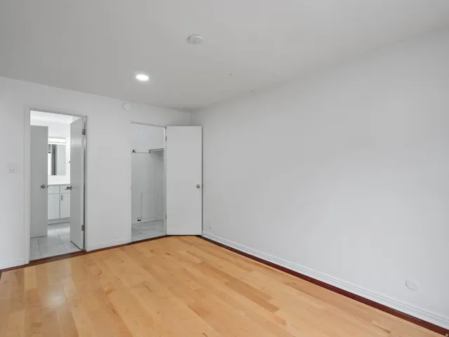 Unfurnished bedroom featuring a spacious closet, light wood finished floors, connected bathroom, and recessed lighting