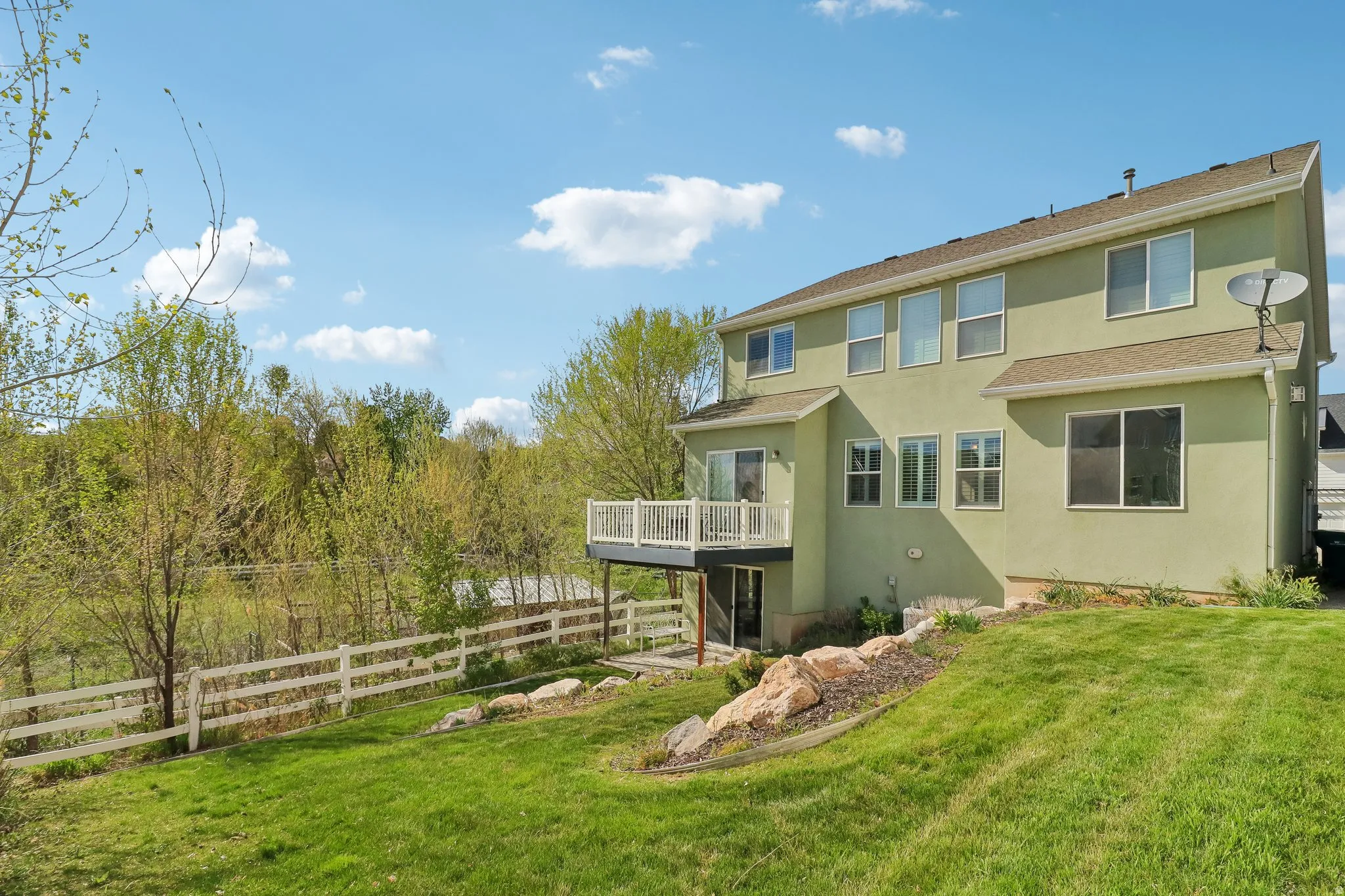 Rear view of house featuring stucco siding and a deck