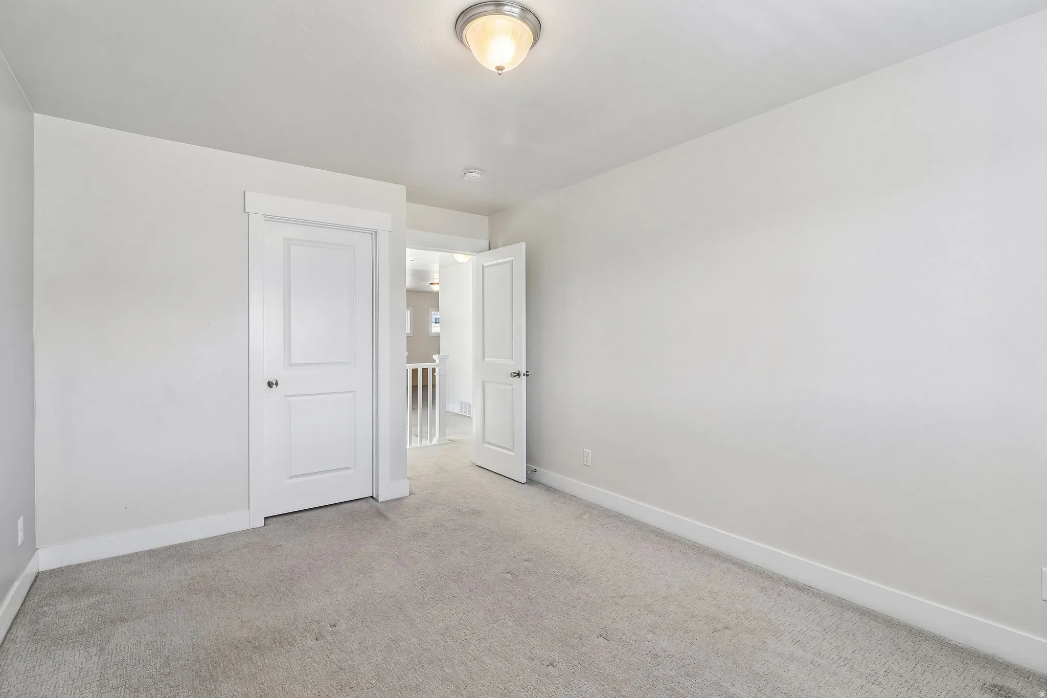 Unfurnished bedroom with light carpet and baseboards
