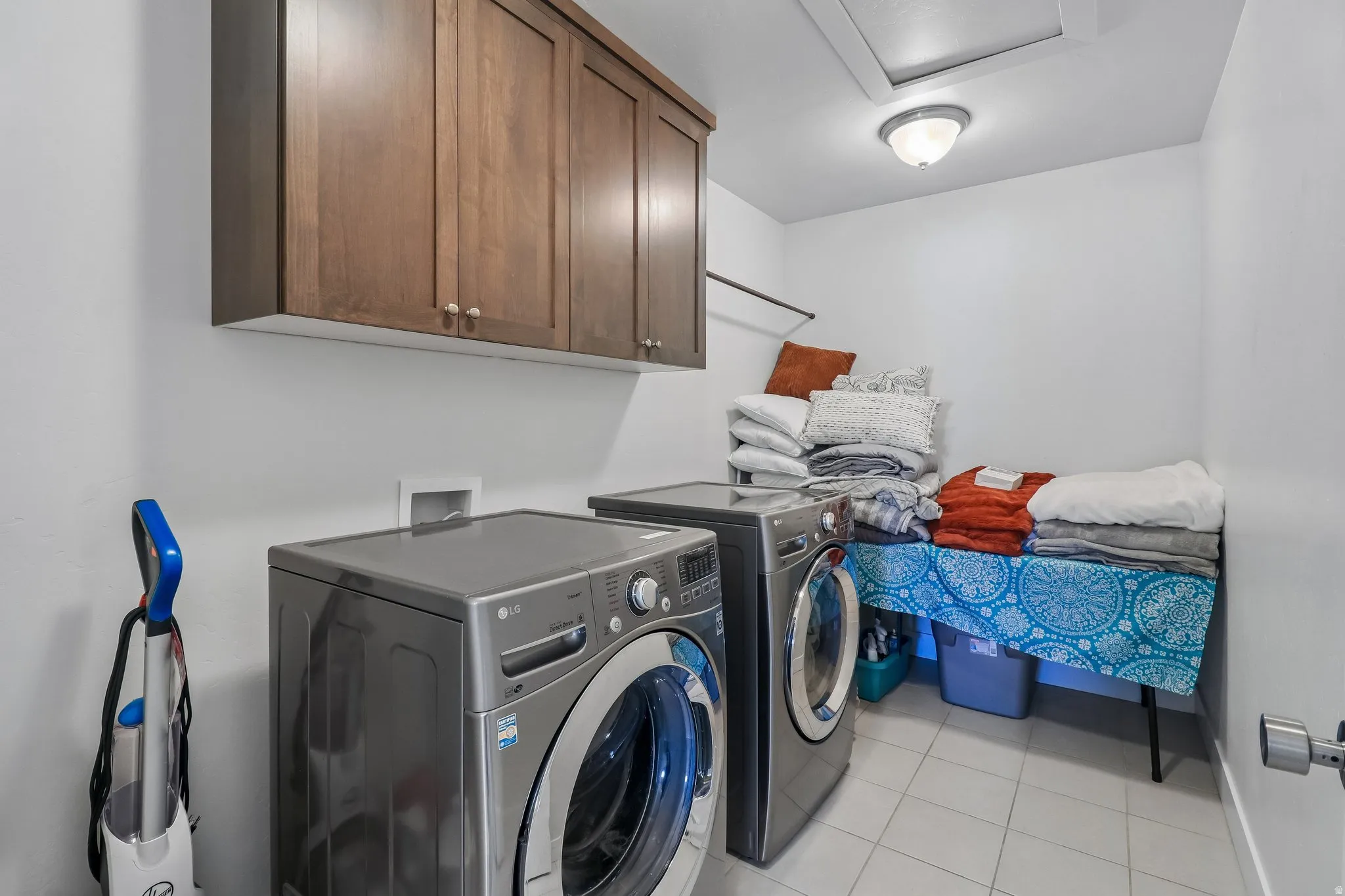 Laundry area with cabinet space, light tile patterned flooring, and washer and dryer