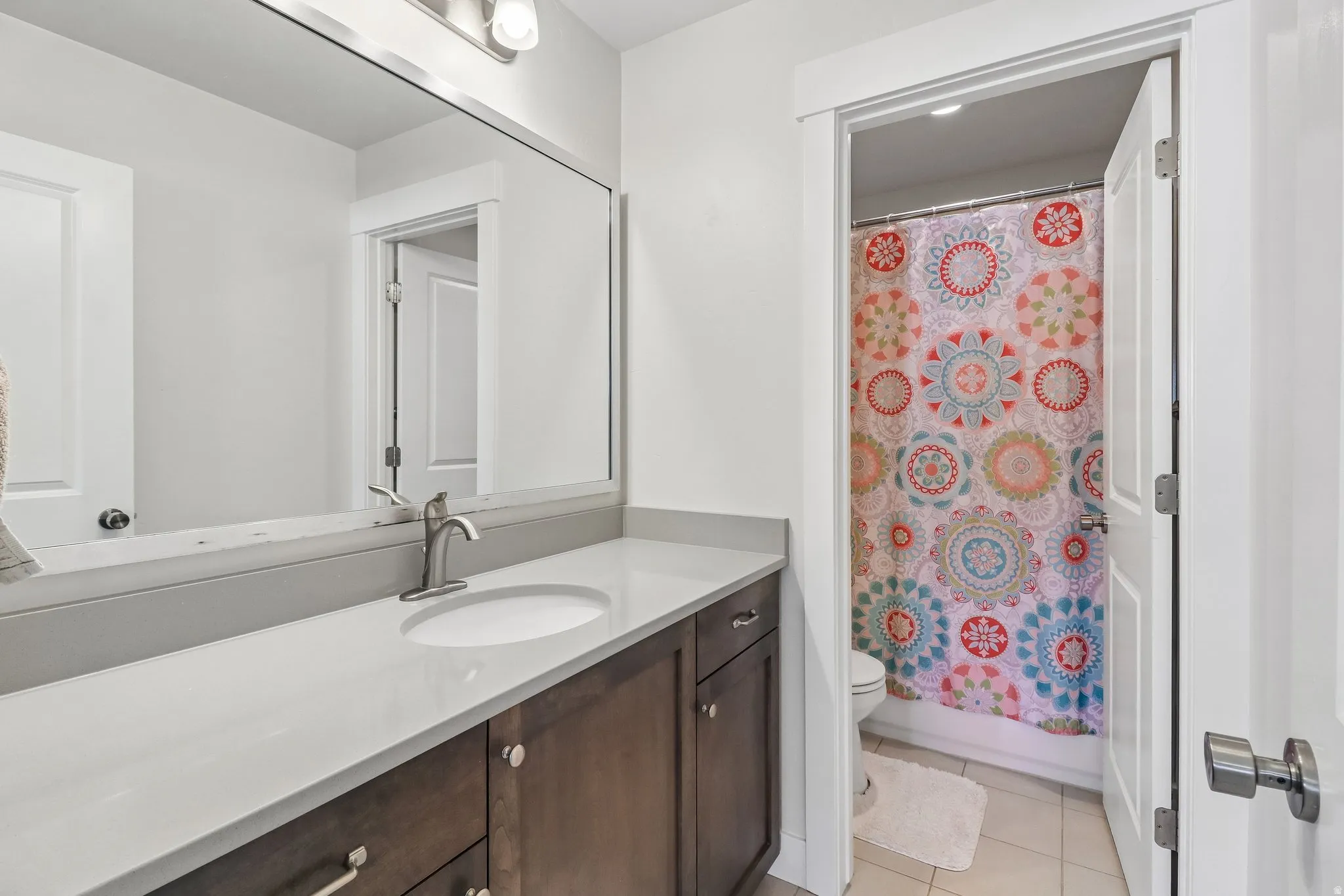 Full bath featuring vanity, light tile patterned floors, and shower / bathtub combination with curtain