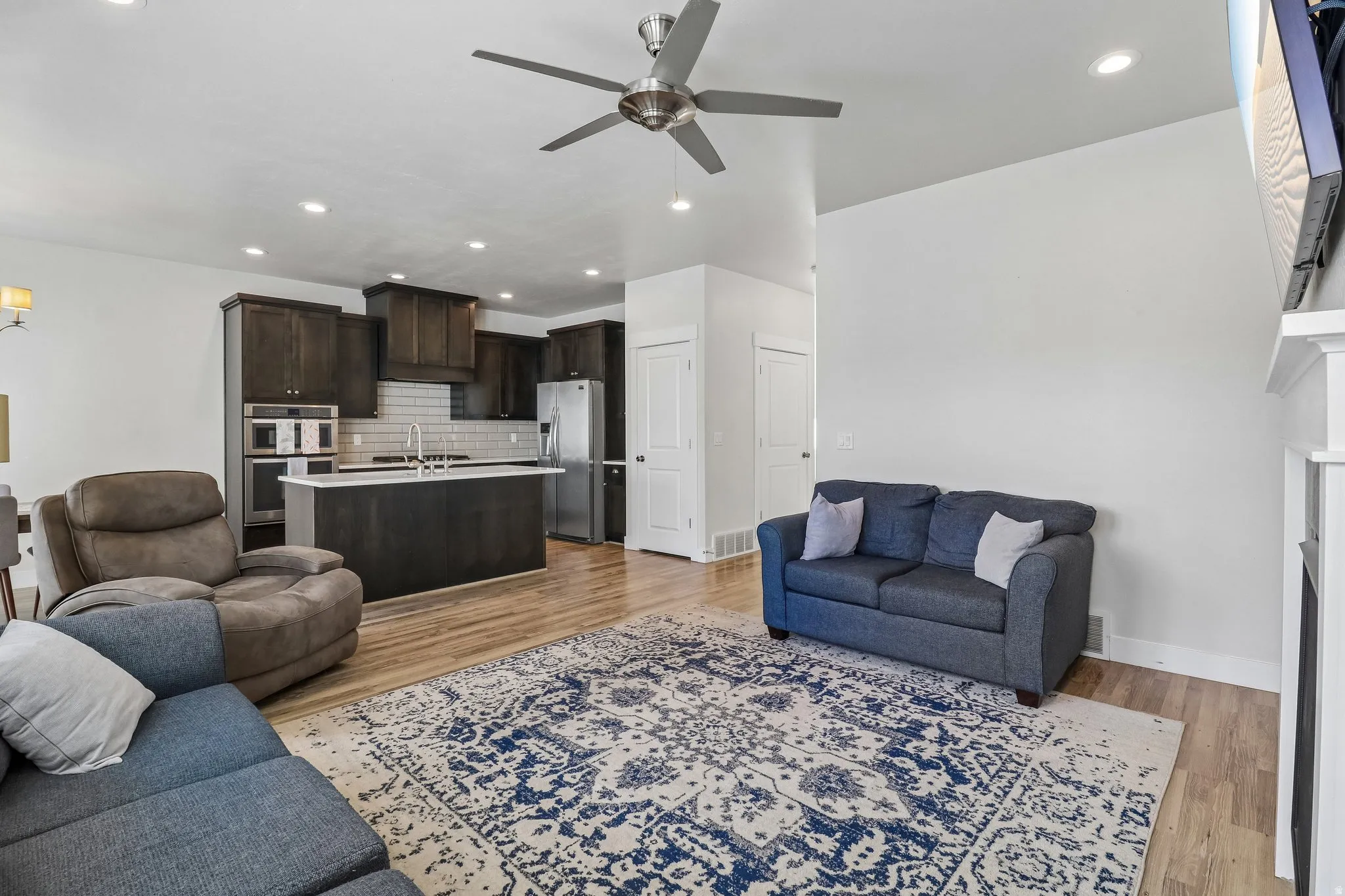 Living room featuring a ceiling fan, light wood-type flooring, recessed lighting, and a fireplace