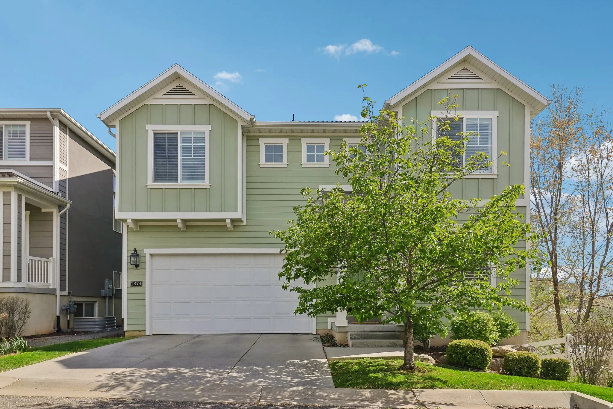 View of front facade featuring board and batten siding, an attached garage, and concrete driveway
