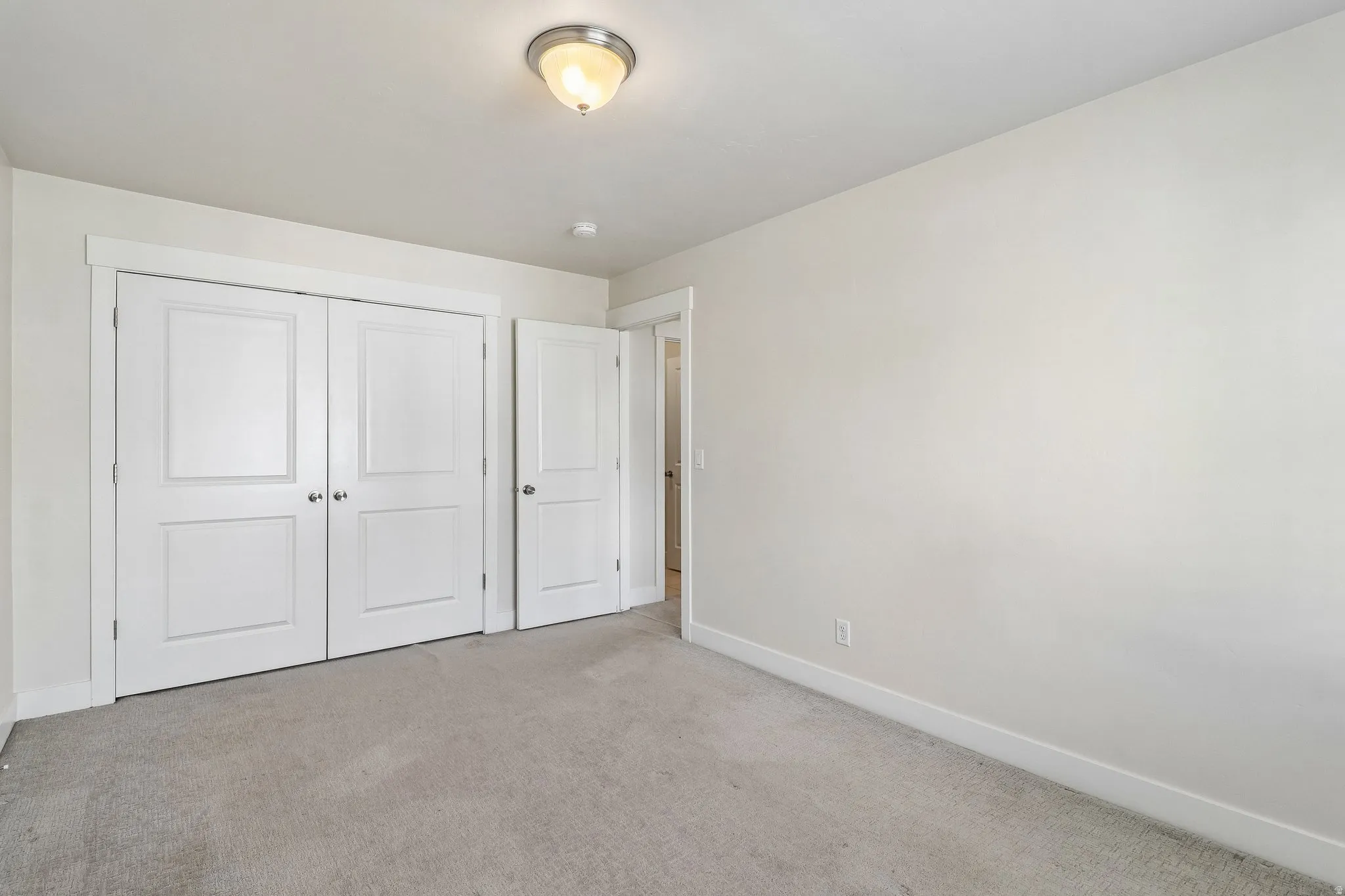 Unfurnished bedroom featuring light carpet and a closet