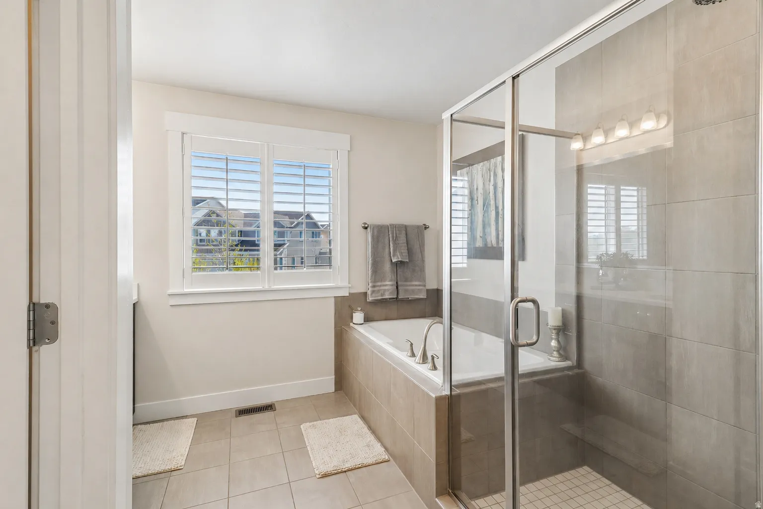 Full bath with a shower stall, light tile patterned floors, and a bath