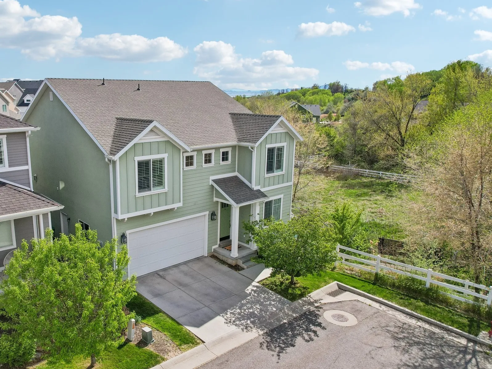 View of front facade featuring board and batten siding, a shingled roof, a garage, and driveway