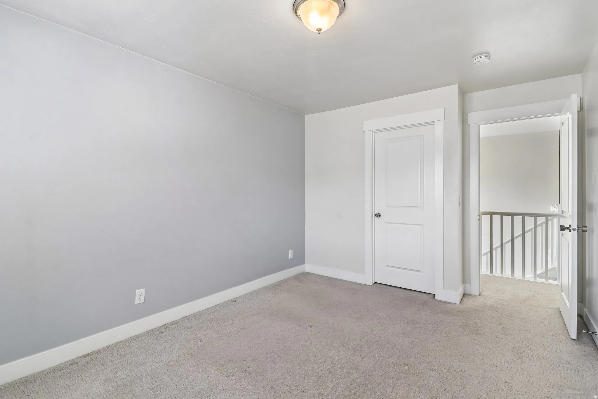 Empty room featuring light colored carpet and a smoke detector