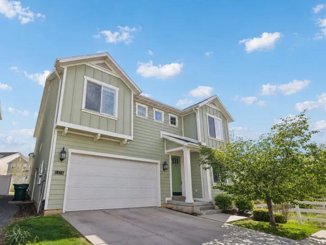 View of front of house with board and batten siding, an attached garage, and driveway