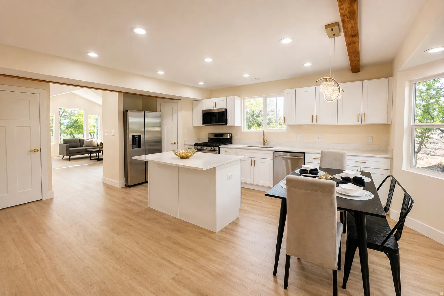 Kitchen featuring stainless steel appliances, a center island, white cabinets, beam ceiling, and light wood-style floors