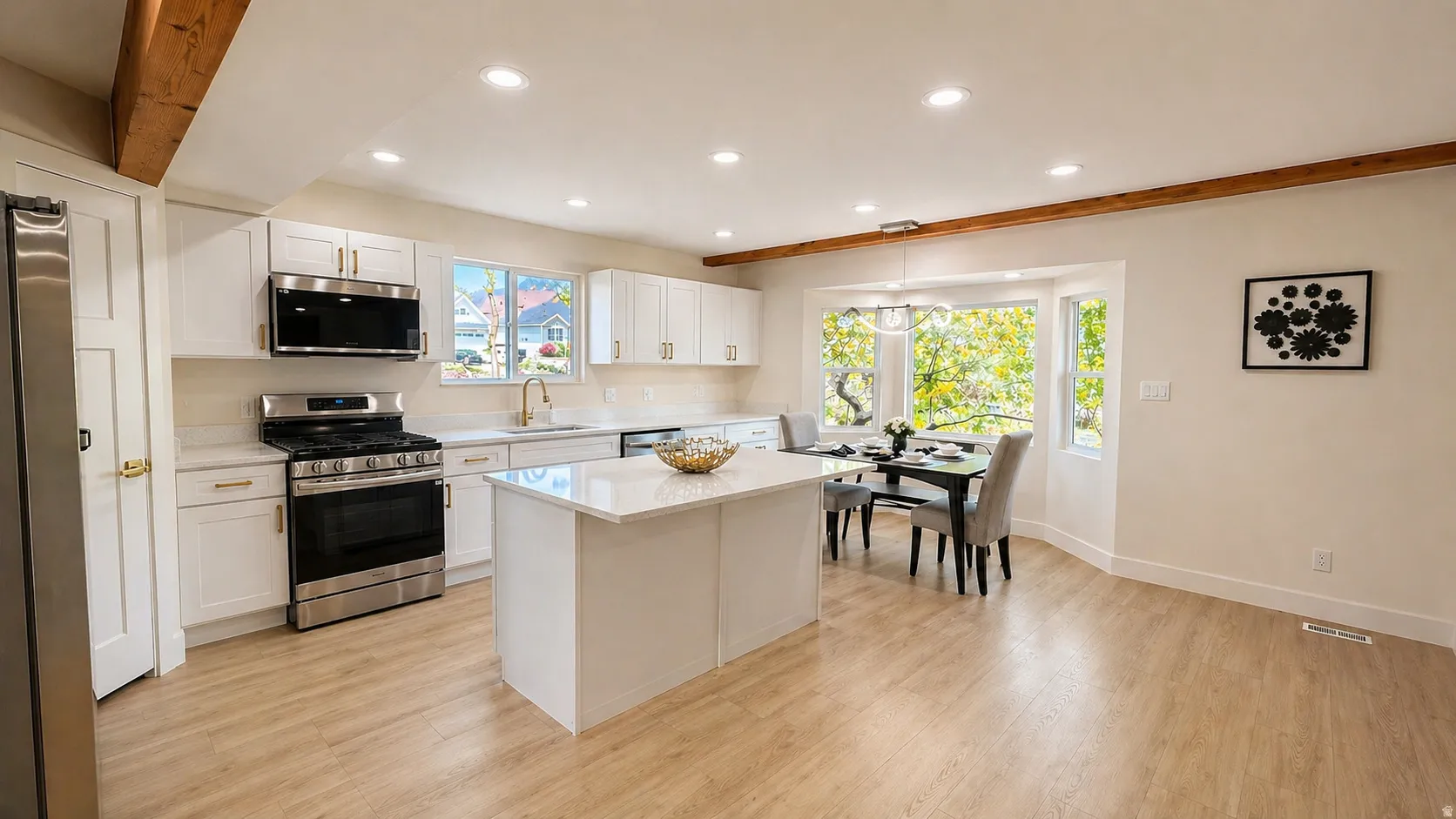 Kitchen featuring stainless steel appliances, white cabinetry, light wood-style floors, a center island, and light stone countertops