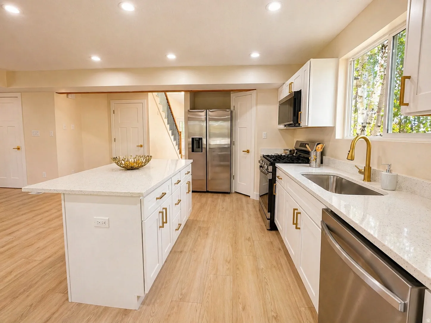 Kitchen featuring stainless steel appliances, white cabinetry, light wood-style flooring, light stone counters, and recessed lighting