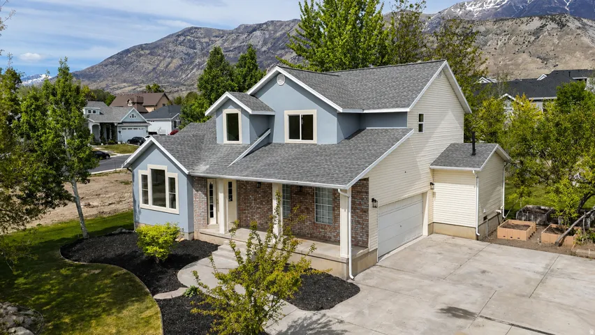 Traditional-style house with a porch, brick siding, concrete driveway, a mountain view, and roof with shingles
