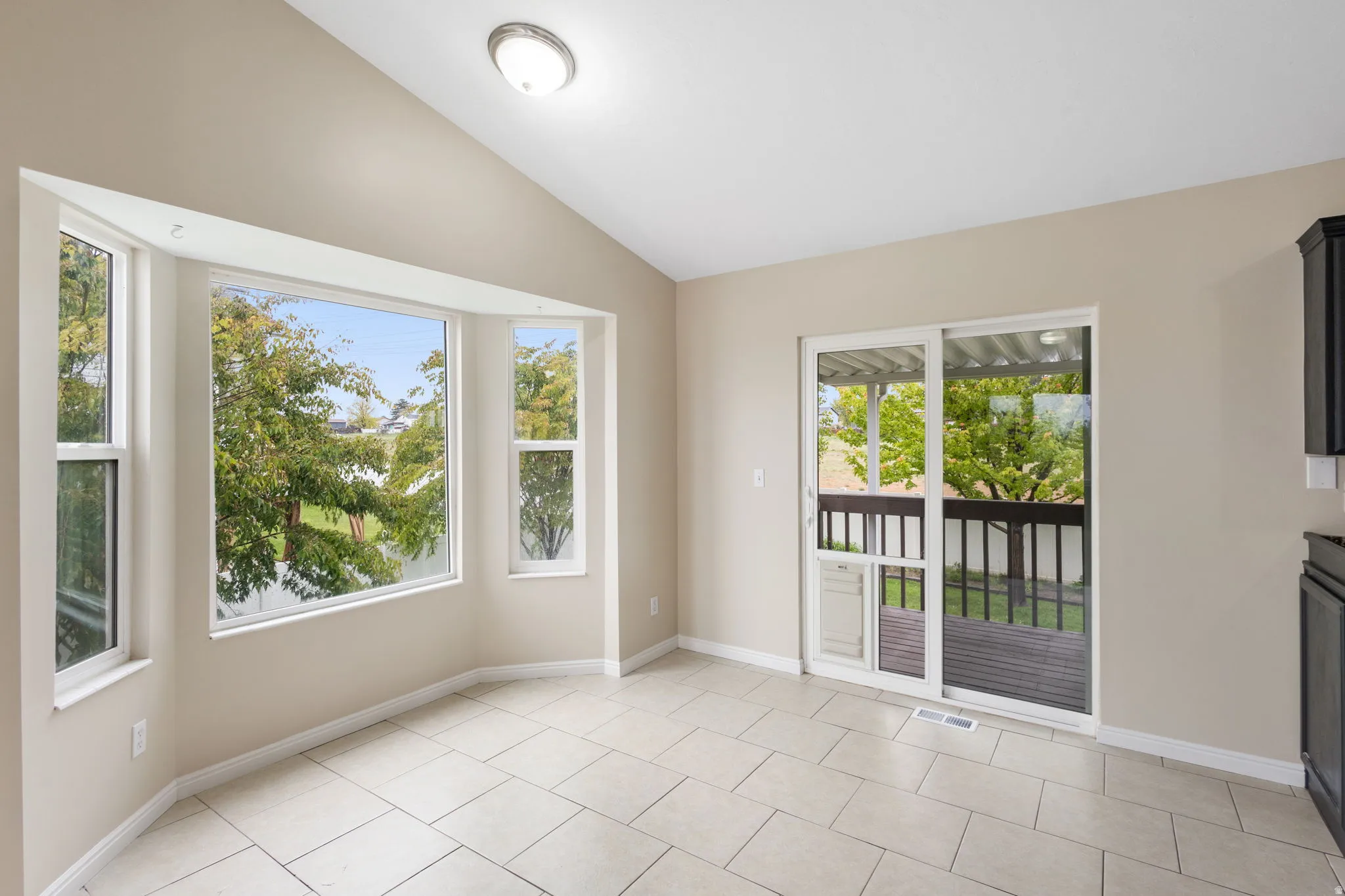 Empty room featuring lofted ceiling and light tile patterned floors