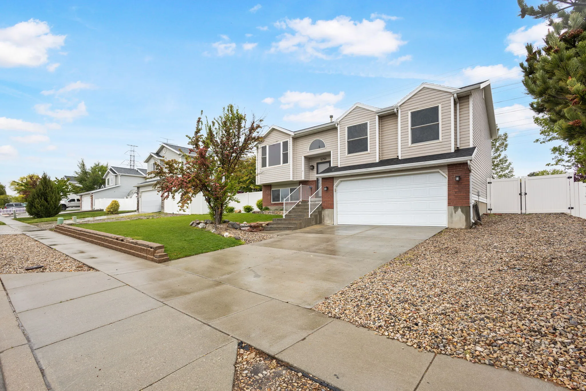 Split foyer home with a gate, driveway, an attached garage, and brick siding