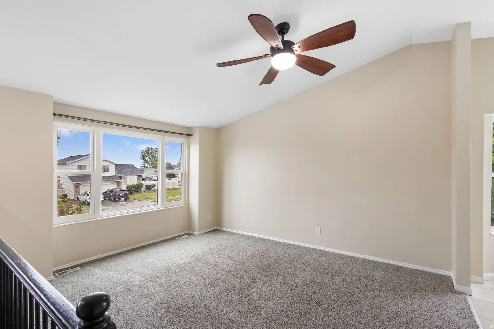 Spare room with light colored carpet, lofted ceiling, and a ceiling fan